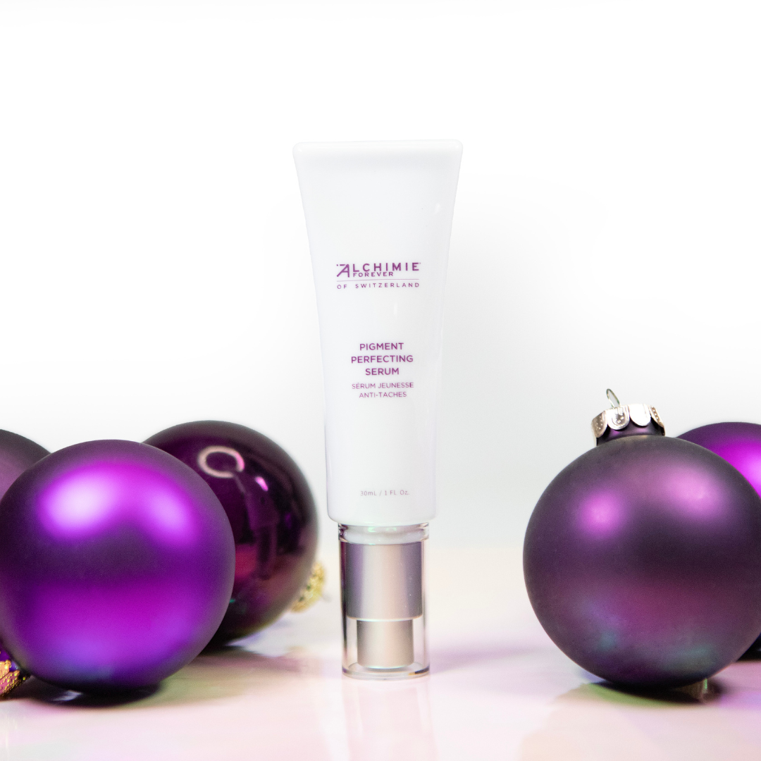 Alchimie Forever Pigment Perfecting Serum bottle with purple Christmas ornaments on a white background